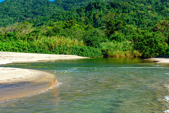 River flowing across the sands of Castelhanos Beach toward the sea on the island of Ilhabela.