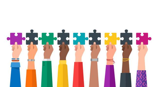 Diverse hands of different skin tones holding colorful jigsaw puzzle pieces up together against a white background, symbolizing team collaboration and representing community inclusion
