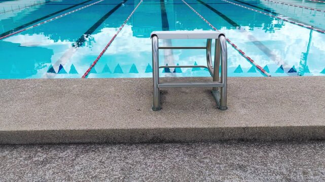 The High angle view of an empty outdoor of olympic size swimming pool with blue water and black lane lines background