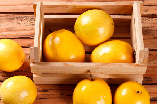 Fresh yellow passion fruits in a rustic wooden crate on a wooden table