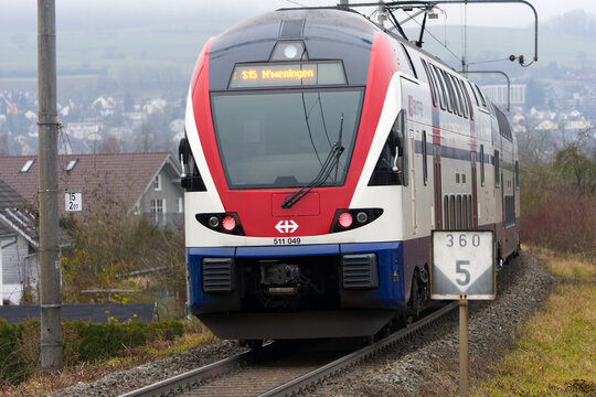 S-Bahn train S15 passing at railway station of Swiss village of Niederhasli on a gray autumn day. Photo taken December 14th, 2025, Zurich Niederhasli Switzerland.