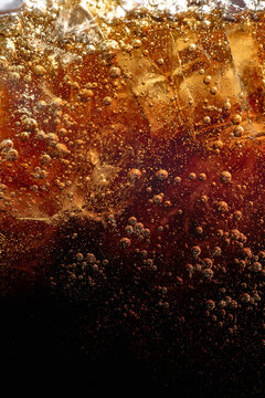 Dark carbonated beverage with ice bubbles and amber splash. Concept of soft drink branding, beverage packaging, fast food advertising, summer refreshment and menu design.