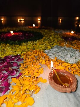 A beautifully arranged floral decoration for Diwali, featuring vibrant yellow and pink petals, accompanied by a lit oil lamp, creating a warm and festive atmosphere.