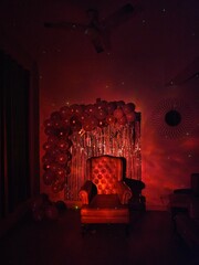 A cozy, illuminated armchair is positioned in a dimly lit room adorned with shimmering balloons, creating a festive and intimate atmosphere perfect for celebrations. © sagar