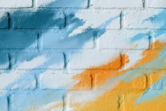 Abstract spray paint art on a white brick wall with bold blue and orange brush strokes creating a modern design.