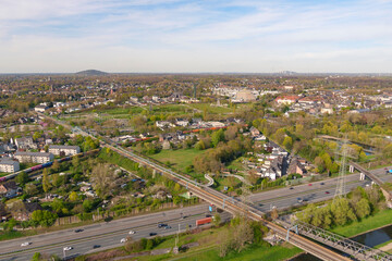 Aerial view of Oberhausen showing residential neighborhoods, railway tracks, a highway, and green open spaces under a clear sky, Oberhausen, Germany. © Visualis