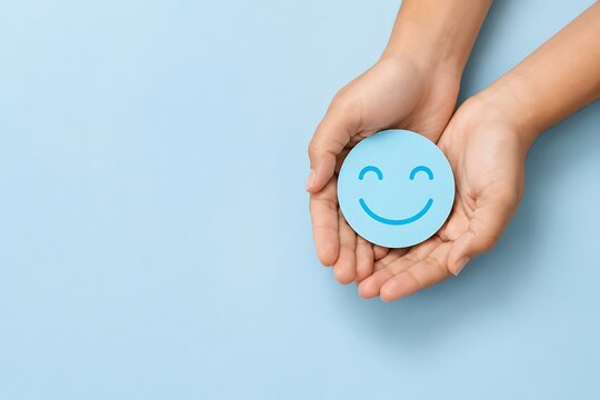 Customer satisfaction concept with a blue smiley face icon held in hands on a light blue background