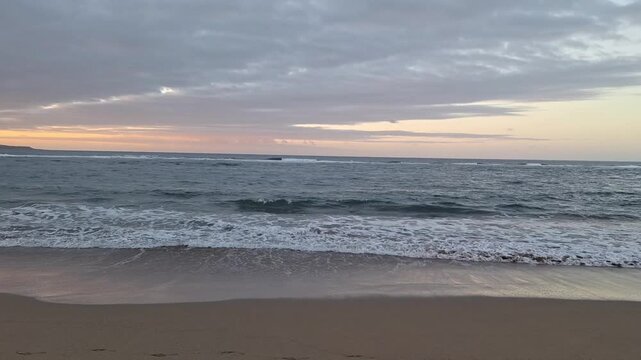 Gentle ocean waves on Playa de Las Canteras under dramatic cloudy sky, Gran Canaria, Canary Islands, Spain