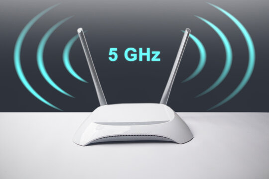 A conceptual image featuring a minimalist white wireless internet router with two antennas, surrounded by glowing blue signal waves and the overlay text 5 GHz.
