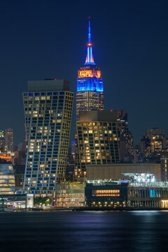 Celebrating America 250 Years and the Knicks game, Illuminated Empire State Building rising above the New York City skyline at blue hour across the Hudson River, New York, USA.