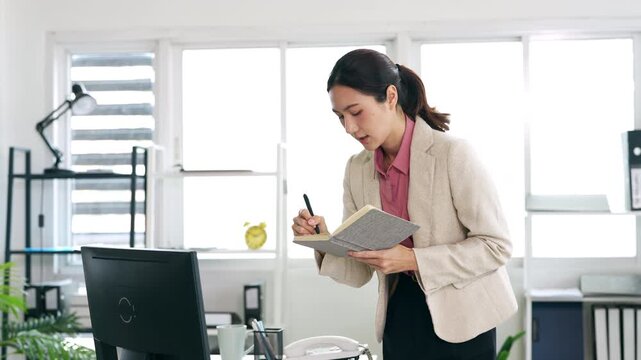 Young businesswoman hand holding pen taking notes , sitting at desk with laptop , analyzing information.