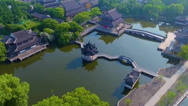 Aerial bird's-eye panorama of Zhouzhuang Ancient Town, classic Jiangnan water town with stone arch bridges, ancient Chinese waterside buildings, canals and lush green trees
