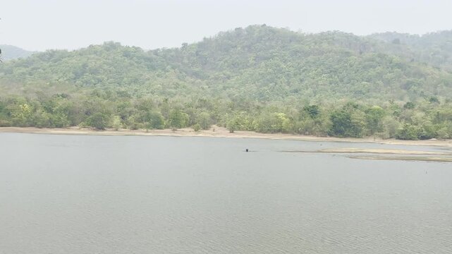 A person casting a fishing net in a reservoir.