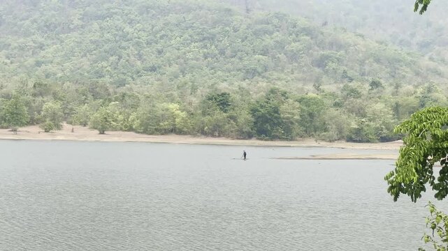 A person casting a fishing net in a reservoir.