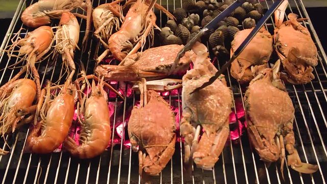 charcoal grilled seafood bbq with shrimp, clam and crab cooking over open fire outdoors during summer picnic