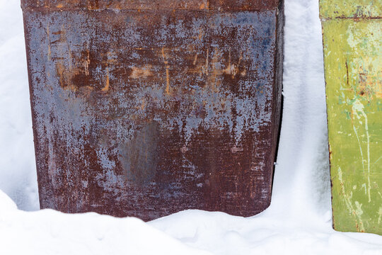 rusty tin wall of outdoor trash container in snow