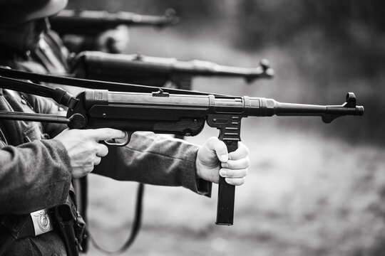 Black and white photo of Wehrmacht soldiers in a firing line. Execution scene, military formation, and WWII reenactment. machine gun shooting