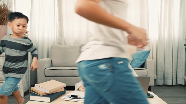 Busy mother working on laptop at home is happily interrupted by children. Children run to surprise her, giving sweet double kiss on cheeks, heartwarming moment of family love, bonding, and happiness