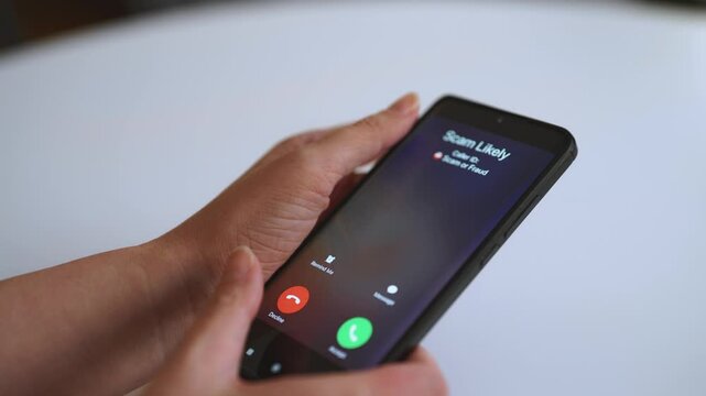 Woman holding smartphone with incoming scam call on screen.