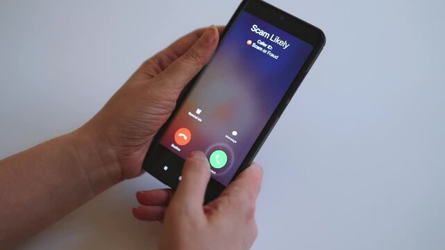 Woman holding smartphone with incoming scam call on screen.