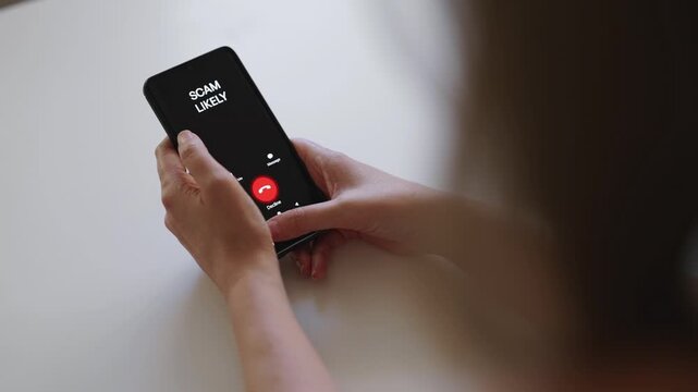Woman holding smartphone with incoming scam call on screen.