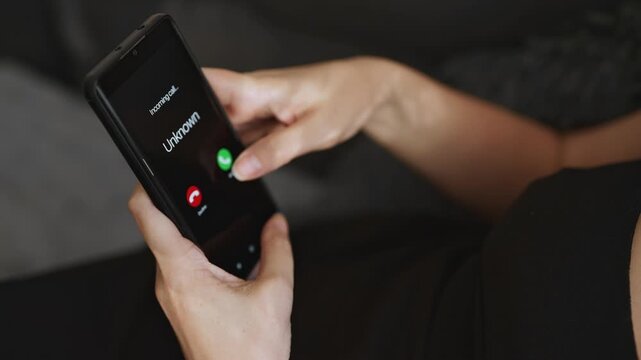 Woman holding smartphone with incoming call from unknown suspicious caller.