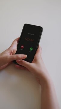 Woman holding smartphone with incoming scam call on screen.
