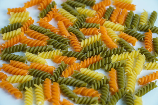 Colorful Uncooked Fusilli Pasta Scattered on White Background