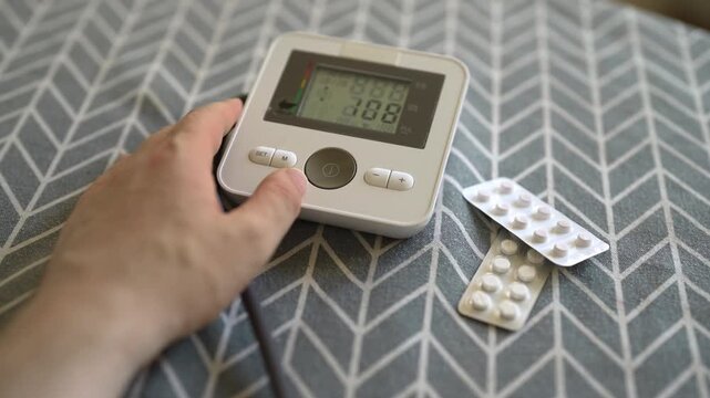 Man measuring blood pressure with digital tonometer at home.