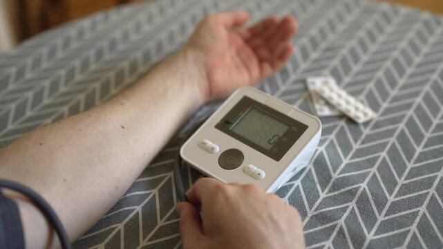 Man measuring blood pressure with digital tonometer at home.