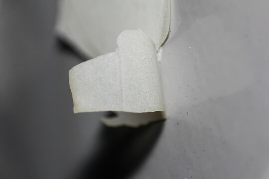 Textured Detail of Light Material Curled and Peeling from Grey Surface