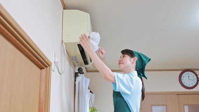 ハンディモップでエアコンを掃除する女性スタッフ