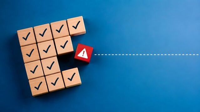 Risk management and human error concept showing red warning block breaking away from grid of wooden checkmark blocks