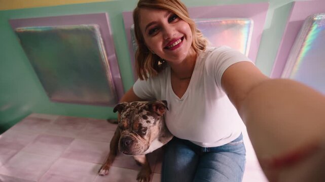 Happy young woman smiling in a selfie with her merle bulldog