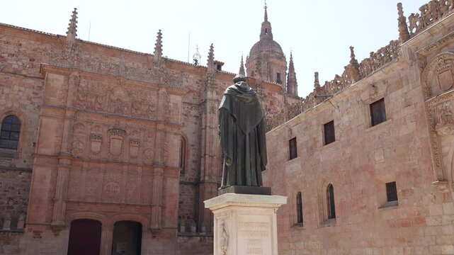 Ornate plateresque facade of the historical University of Salamanca with Fray Luis de Leon statue and cathedral tower, Spain