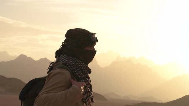 Epic desert survivor man nomad face covered walking horizontal back view landscape.
