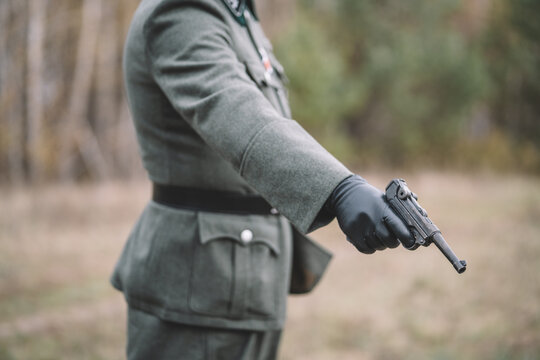 Close-up of a German officer aiming a pistol during a World War II historical reenactment. 