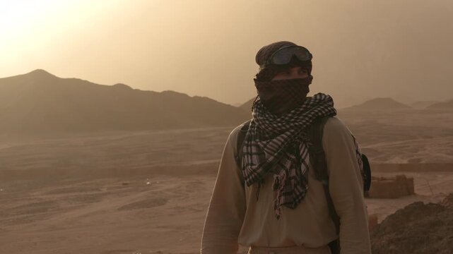 Epic desert survivor man nomad face covered walking horizontal back view landscape.
