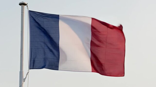 Video of the French flag waving in the wind tied to a white flagpole