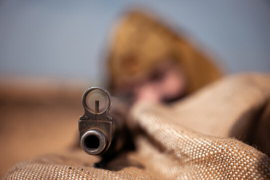 Front view through the sights of rifle held by a Soviet sniper during a World War II military reenactment. Concept of Eastern Front combat, battlefield tension, and historical reconstruction.