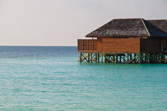 Maldives overwater bungalow offers a peaceful retreat, providing a concept of luxury travel and tropical vacation with its traditional wooden architecture blending into the serene turquoise ocean