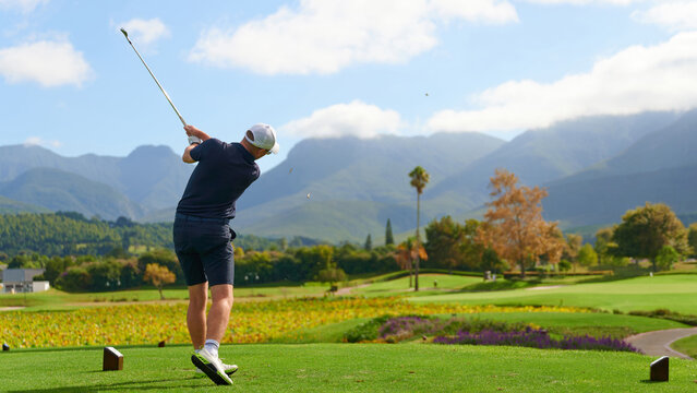 Man swinging golf club on golf course.