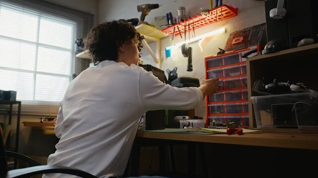 Young adult Asian man assembling desktop computer at workshop desk, picking small parts from organizer. Clip is ideal for IT support services, hardware tutorials, and technology education