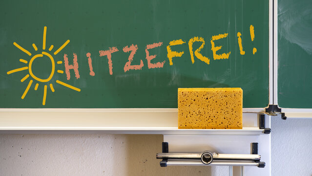 Hitzewelle - Hitzefrei an deutscher Schule - Lehrer schreibt deutschen Text mit Kreide an gr&uuml;ne Schultafel