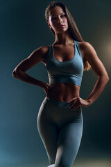 Obraz premium fitness woman in sensual sportswear posing confidently in studio, athletic female model showcasing modern activewear in studio portrait, confident sporty woman wearing fashionable fitness apparel 
