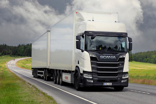 White Scania R660 truck pulls freight trailer on rural highway, moody sky background. Long transport. 