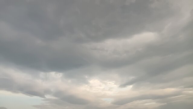 Sunlight breaking through heavy gray storm clouds in overcast sky
