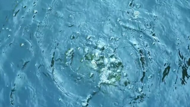 Close up of water bubbles and ripples on blue surface, abstract liquid texture, natural aquatic background, realistic 4k motion video footage
