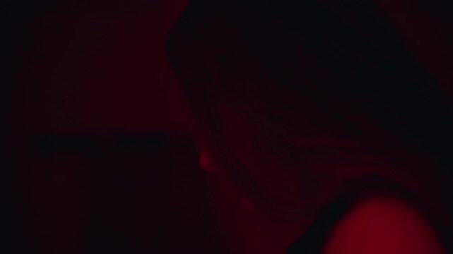 Side View of Young Woman Pressing Artificial Vampire Fang Into Place Under Red Light During Halloween Costume Preparation, Horror Costume, Spooky Celebration
