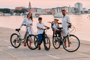 Fototapeta premium Family Biking at Sunset Along the Waterfront in Umag, Croatia With Parents and Children on Bikes